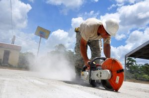 worker cutting concrete with industrial saw