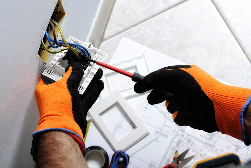 closeup of electrician hands working on an electrical outlet